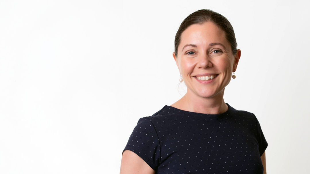 Serena Gundy wearing navy blue t shirt with polka dots, pictured smiling against a white background